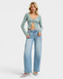 Woman wearing a light blue cardigan and jeans on a white background