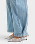 Close-up of light blue jeans and silver high-heeled shoes on a white background