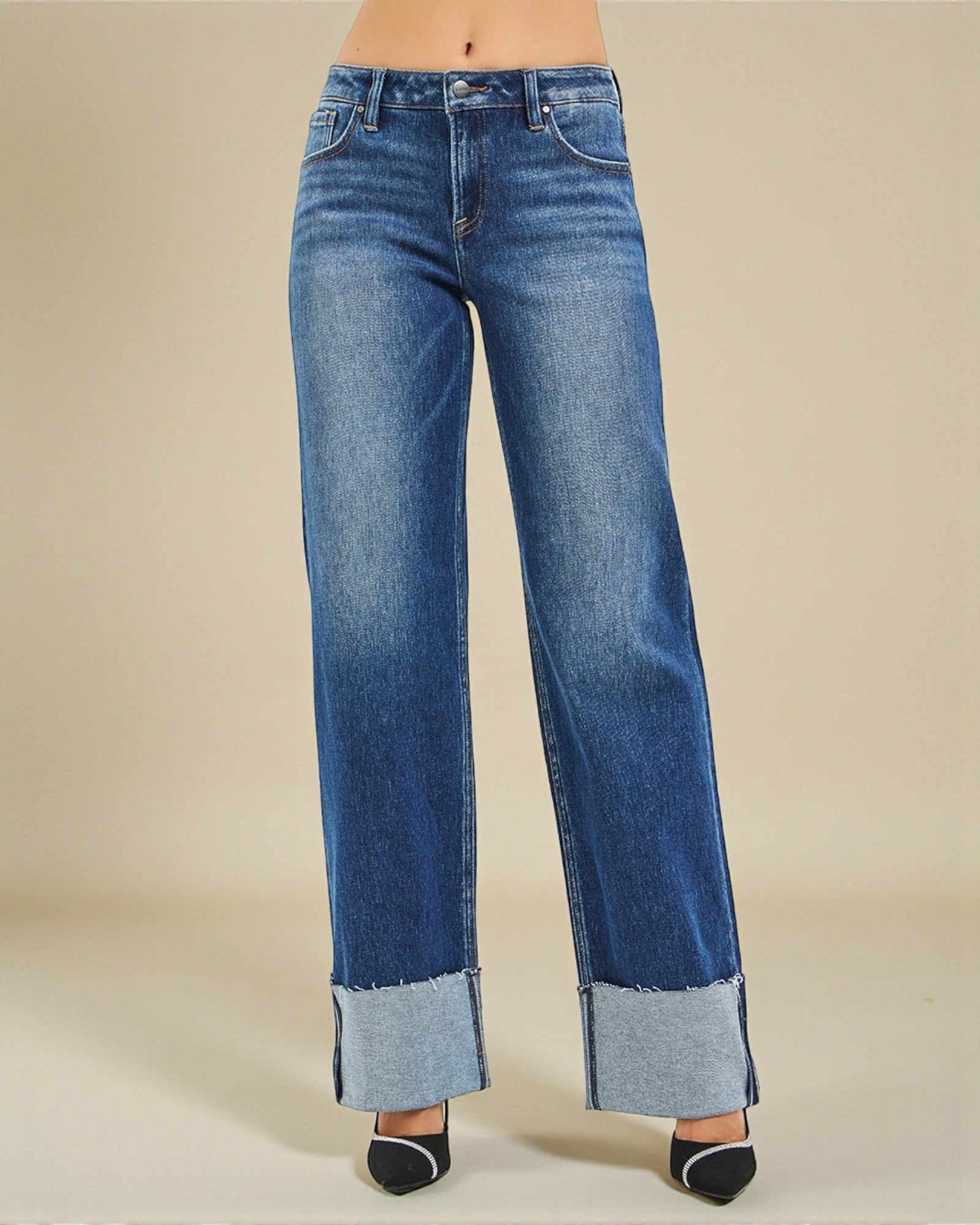 Blue jeans with cuffed hems on a beige background