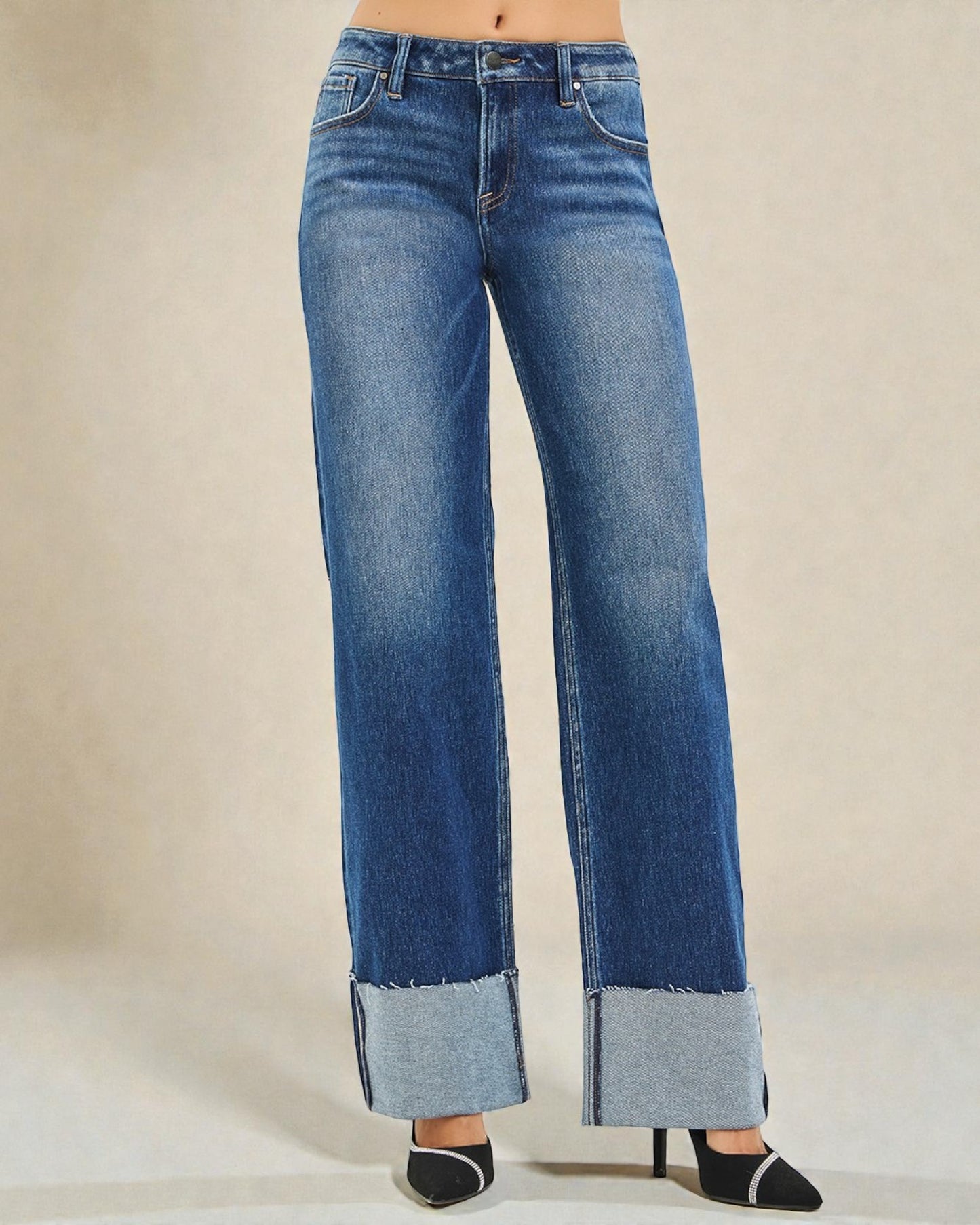 Blue jeans with a rolled-up hem on a beige background