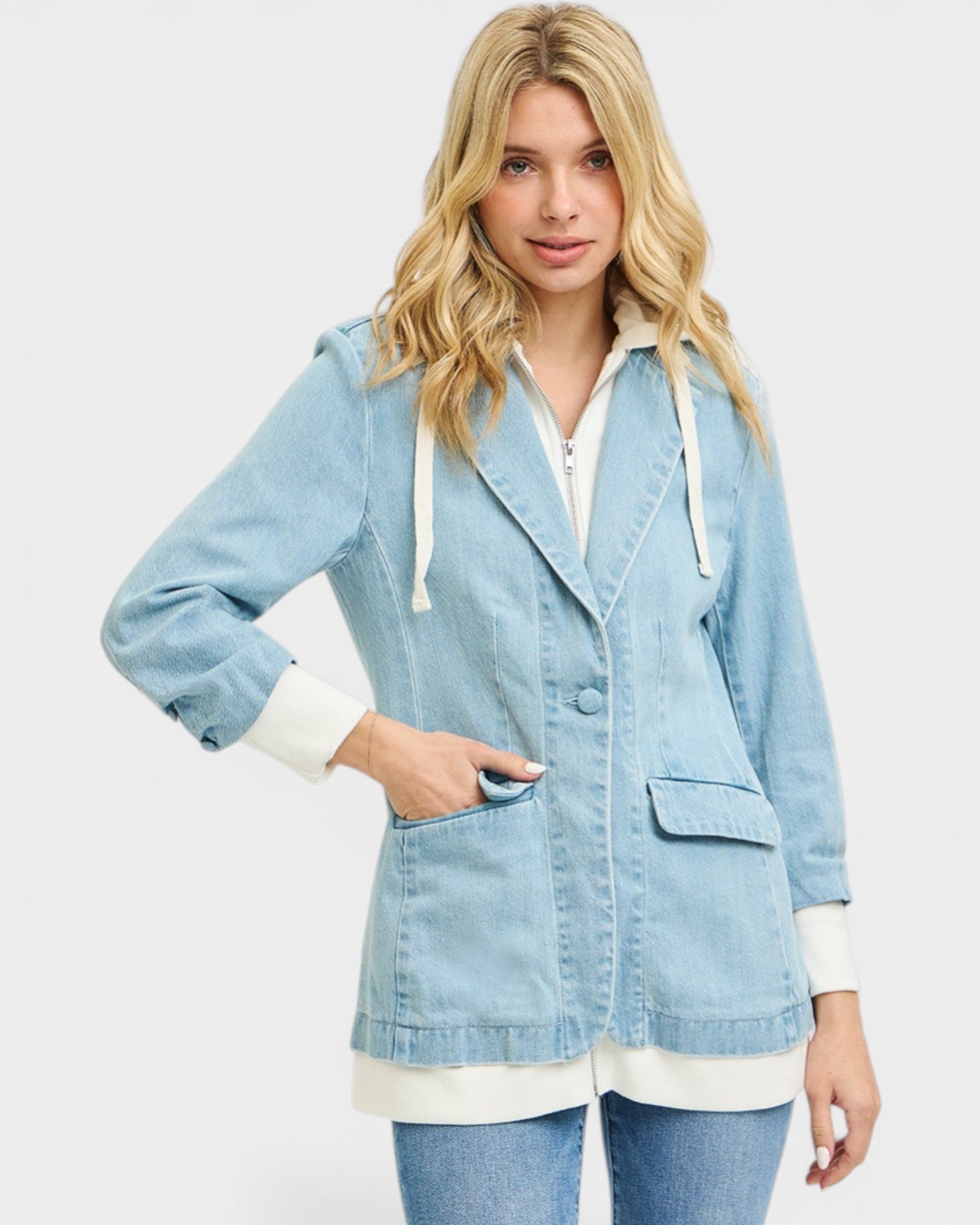 Woman wearing a light blue denim jacket with white trim on a plain background