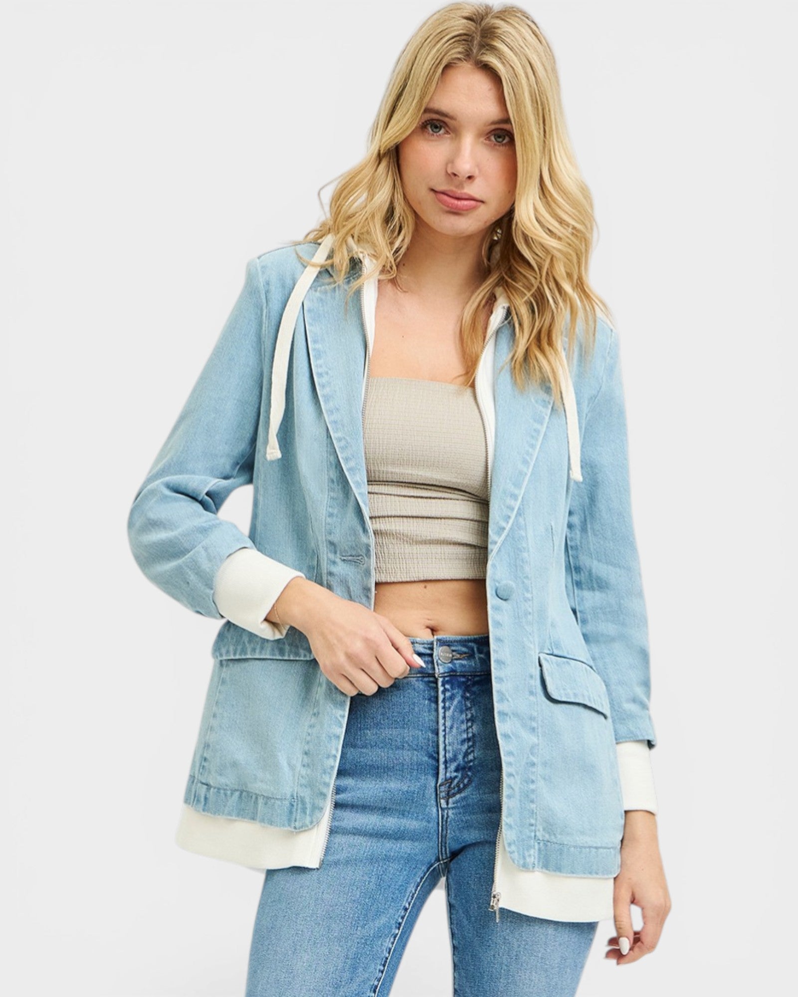Woman wearing a light blue denim jacket with white trim on a plain background