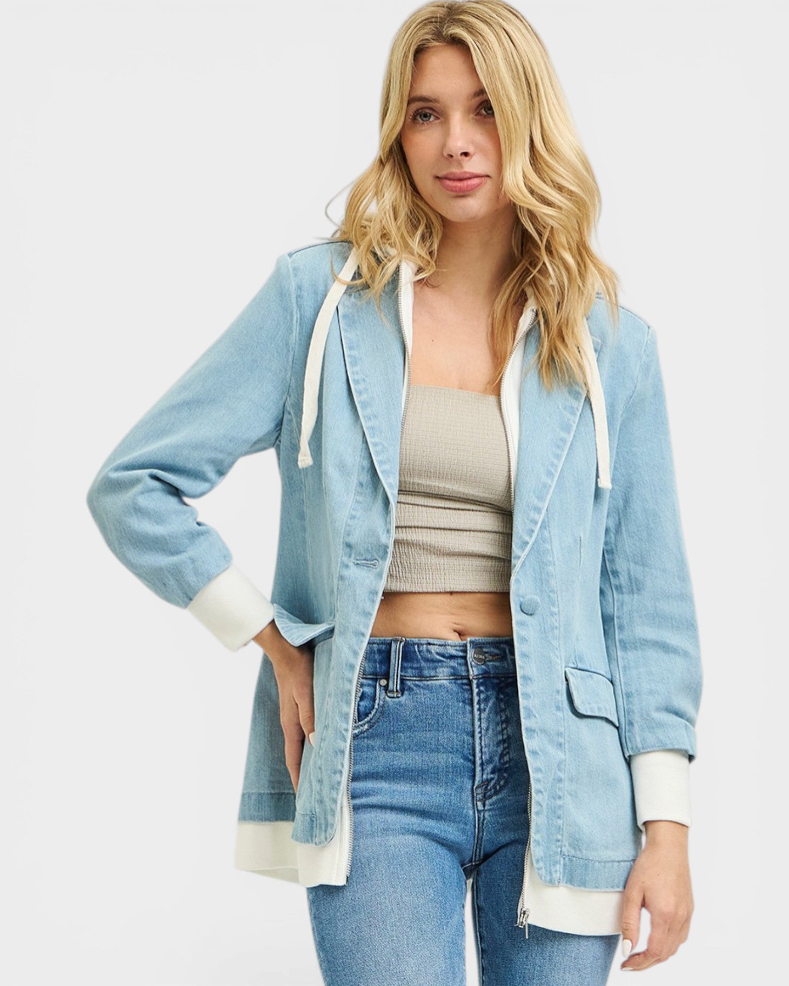 Woman wearing a light blue denim jacket with white trim on a plain background