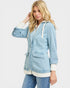Woman wearing a light blue denim jacket with white trim on a plain background