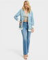 Woman wearing a light blue denim jacket and jeans on a white background