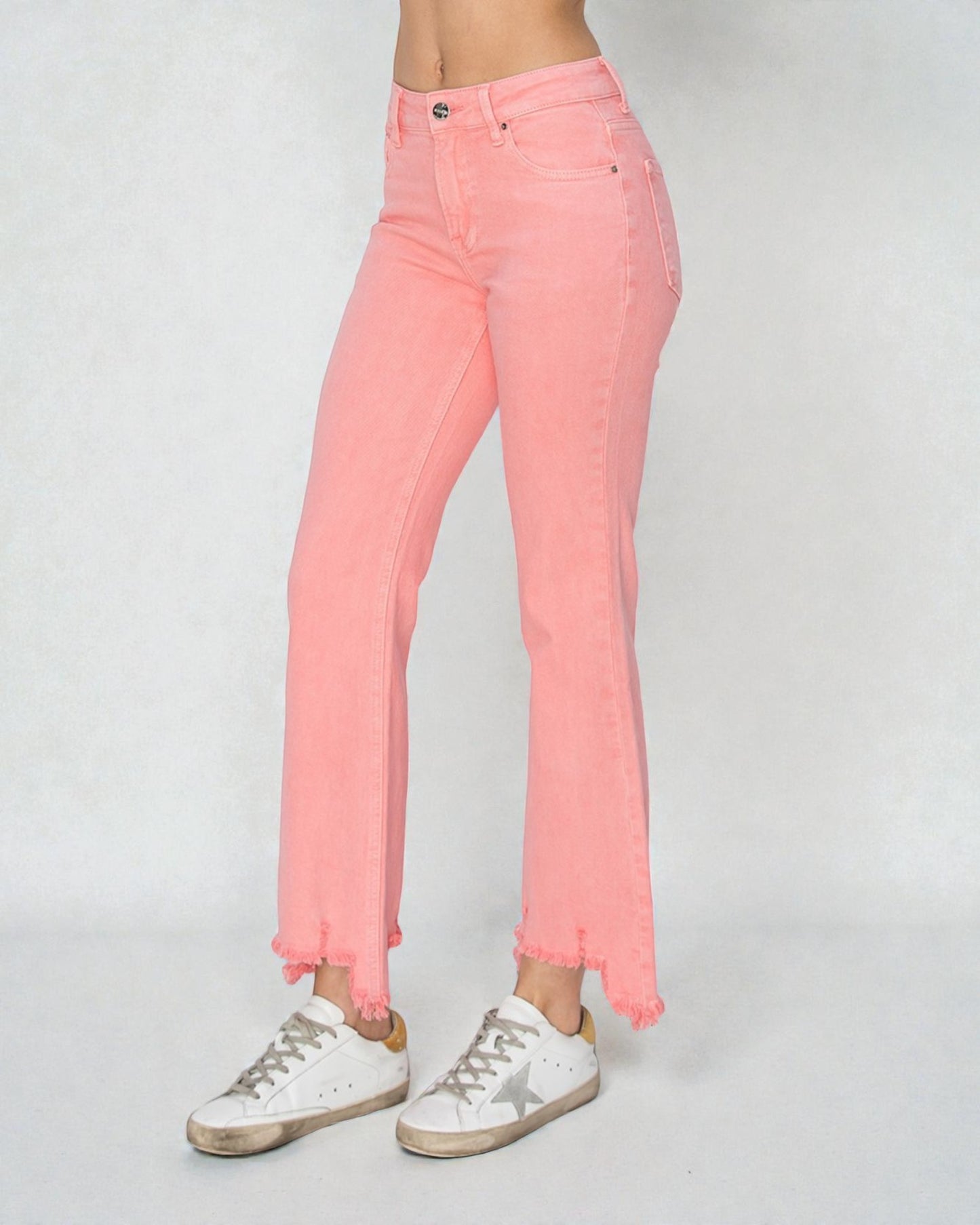 Person wearing pink jeans and white sneakers on a plain background