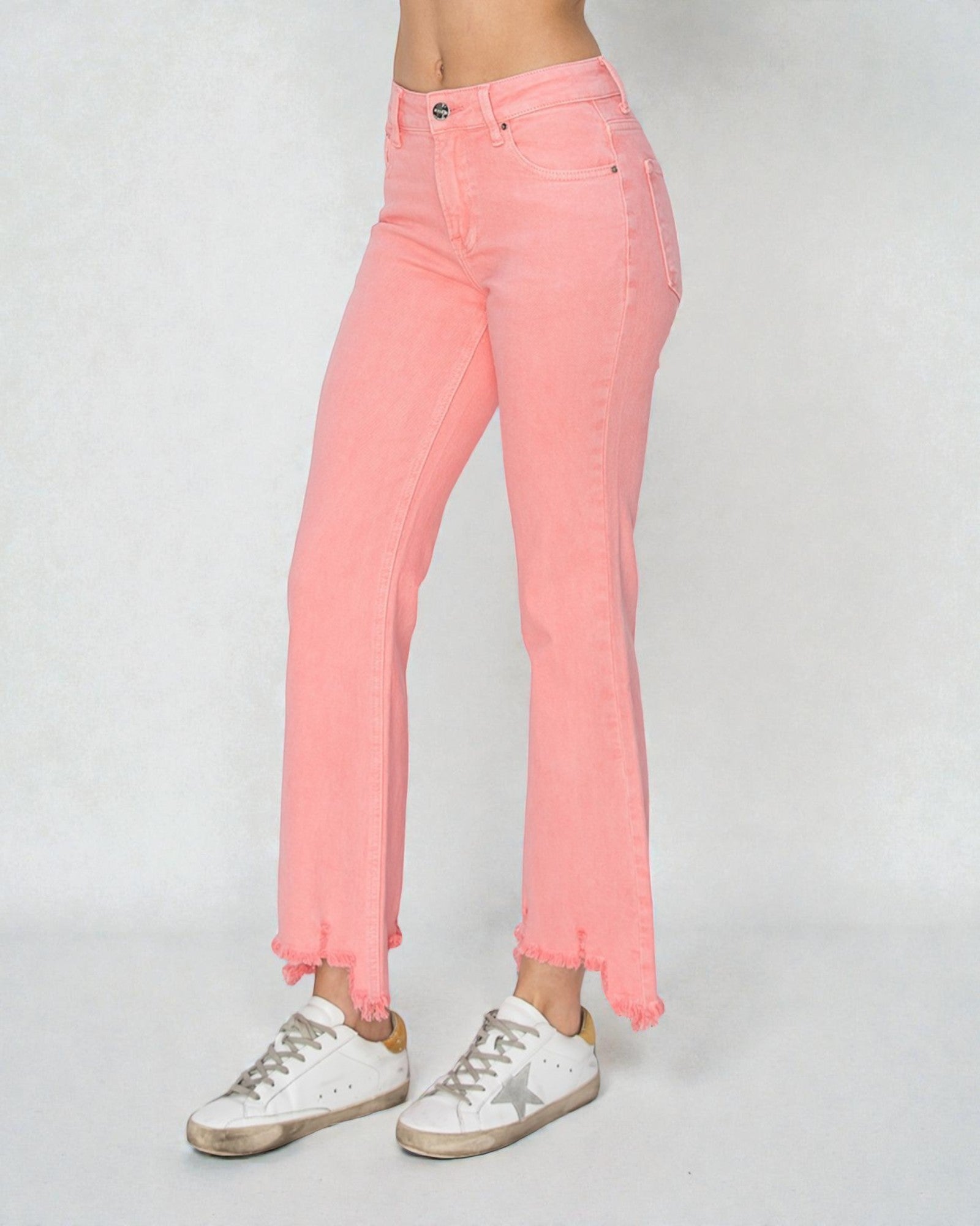 Person wearing pink jeans and white sneakers on a plain background