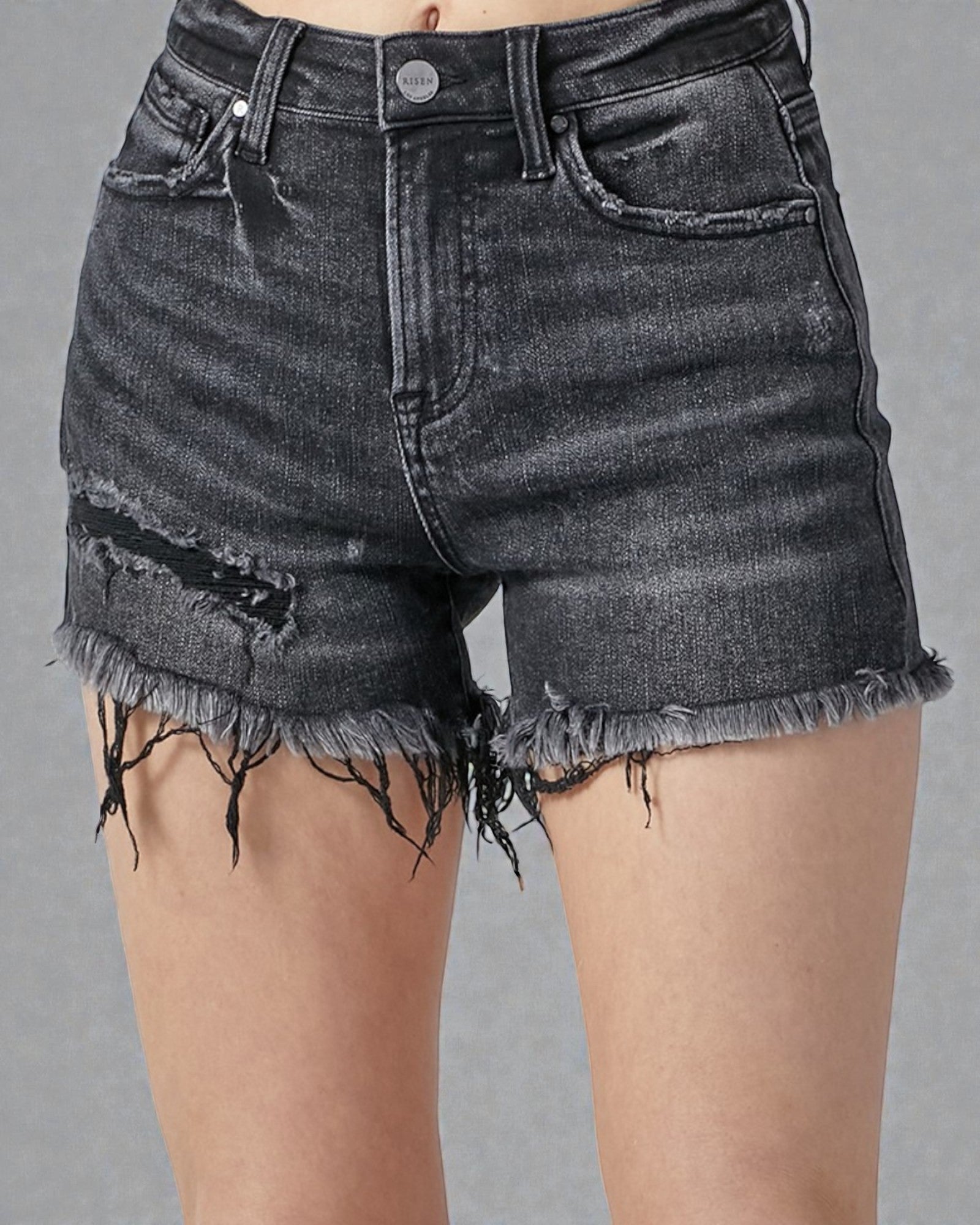 Black denim shorts with frayed edges on a gray background