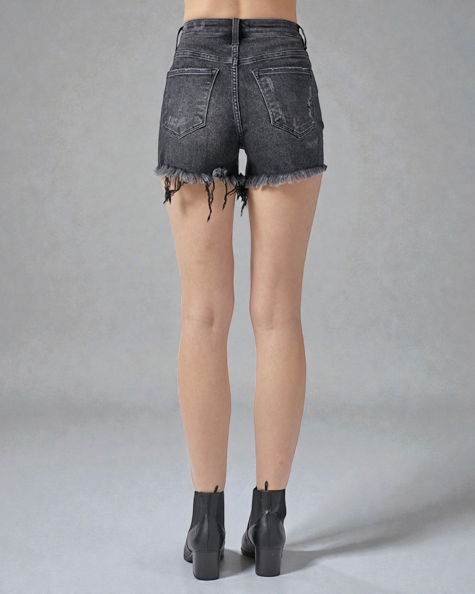 Black denim shorts worn by a person on a gray background