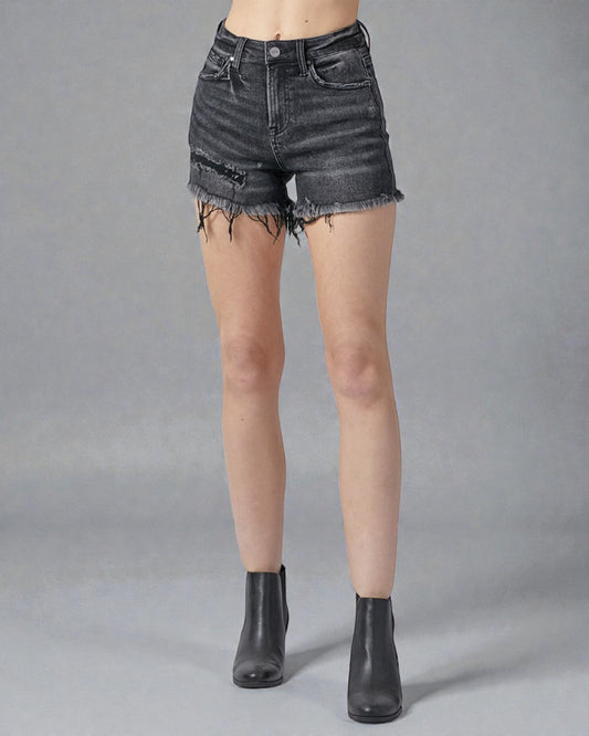 Person wearing black denim shorts on a gray background