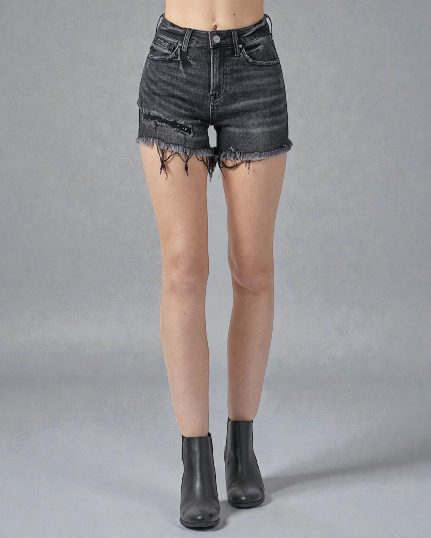 Person wearing black denim shorts on a gray background