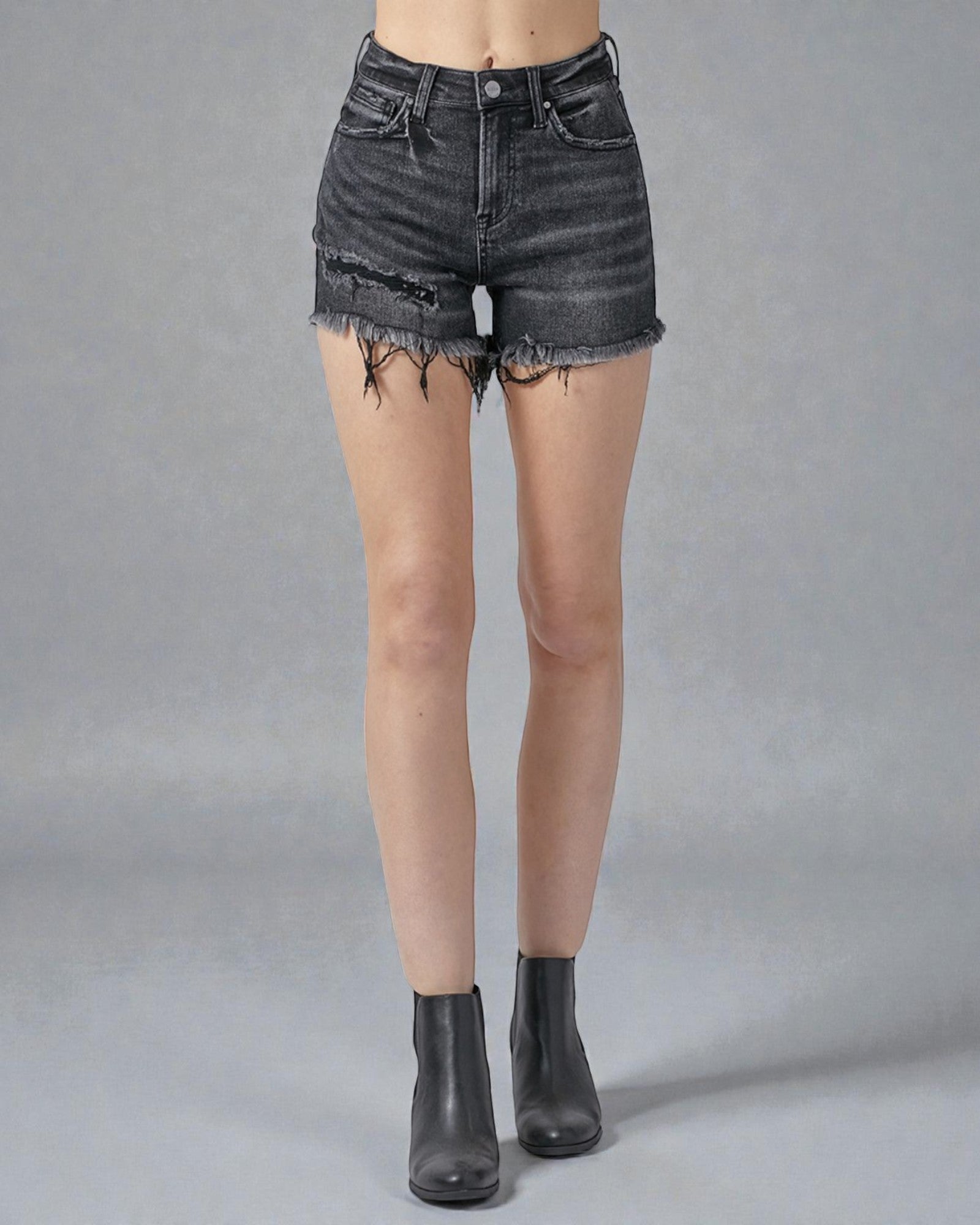 Person wearing black denim shorts on a gray background