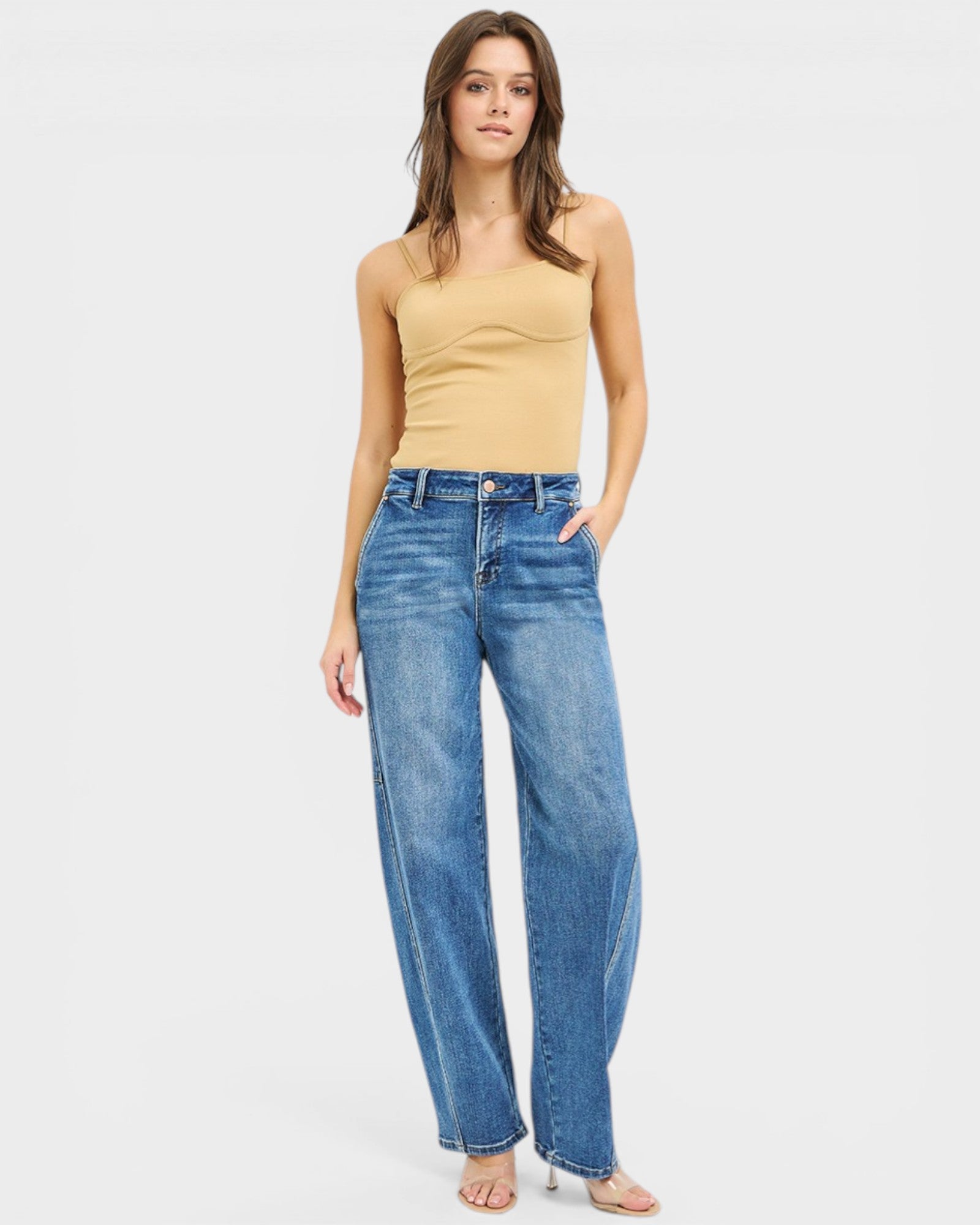 Woman wearing blue jeans and a beige top on a white background