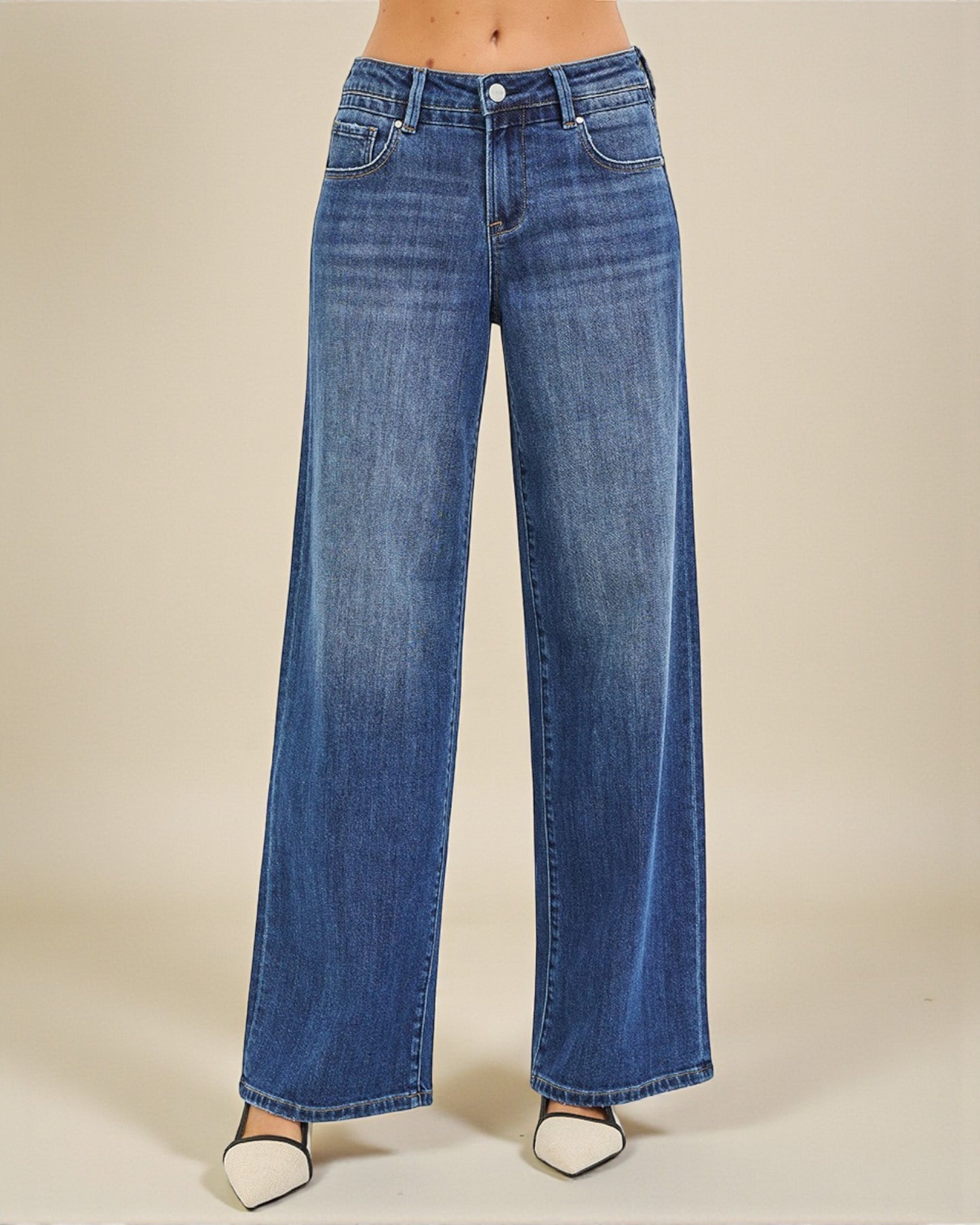 Blue jeans worn by a person on a beige background