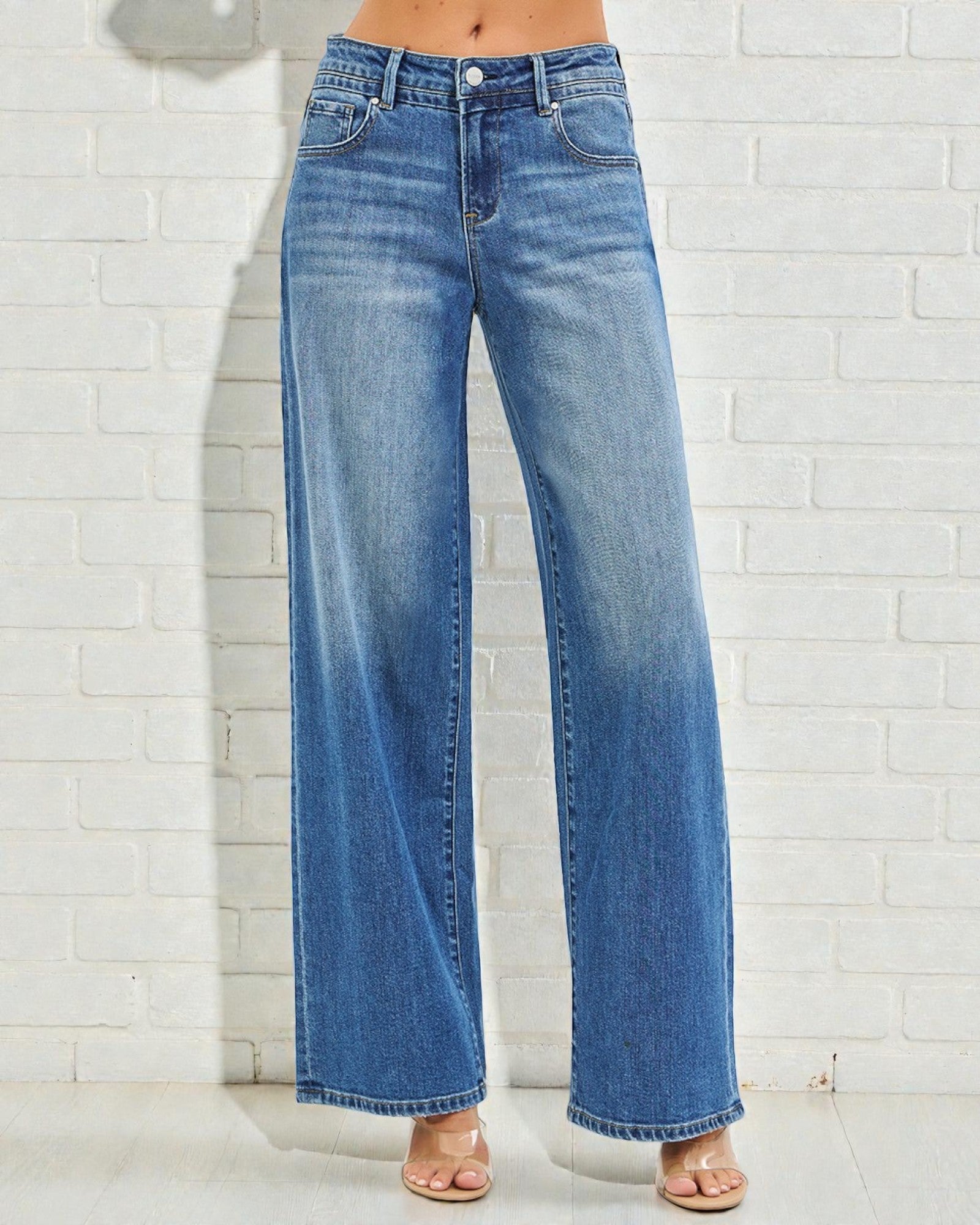 Blue jeans worn by a person against a white brick wall.