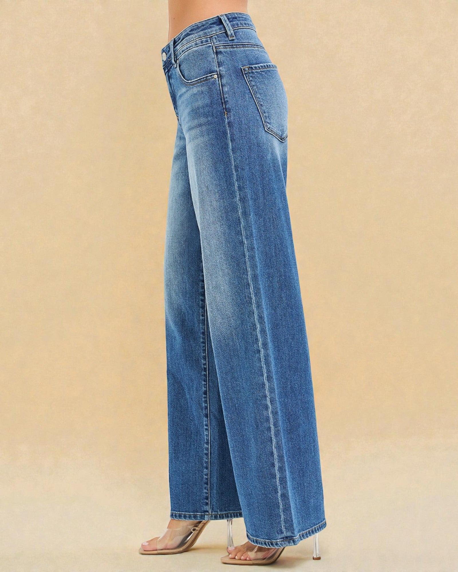 Blue jeans worn by a person on a beige background