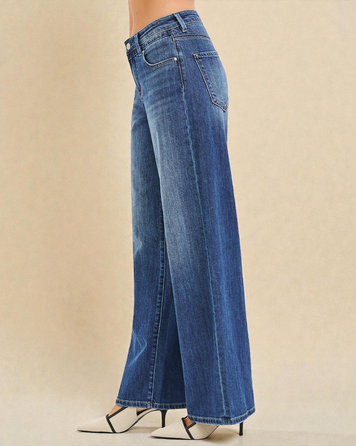 Blue jeans worn by a person on a beige background