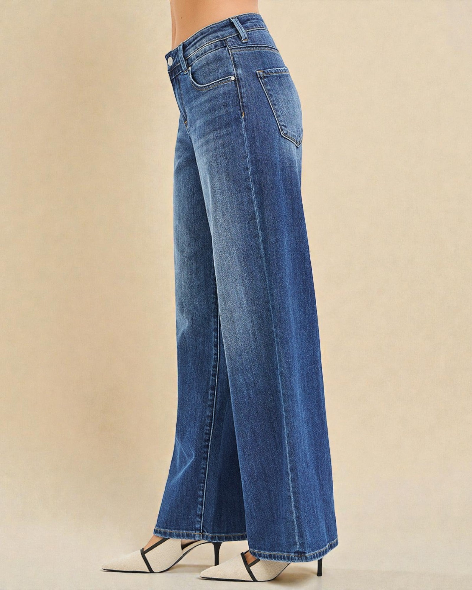 Blue jeans worn by a person on a beige background