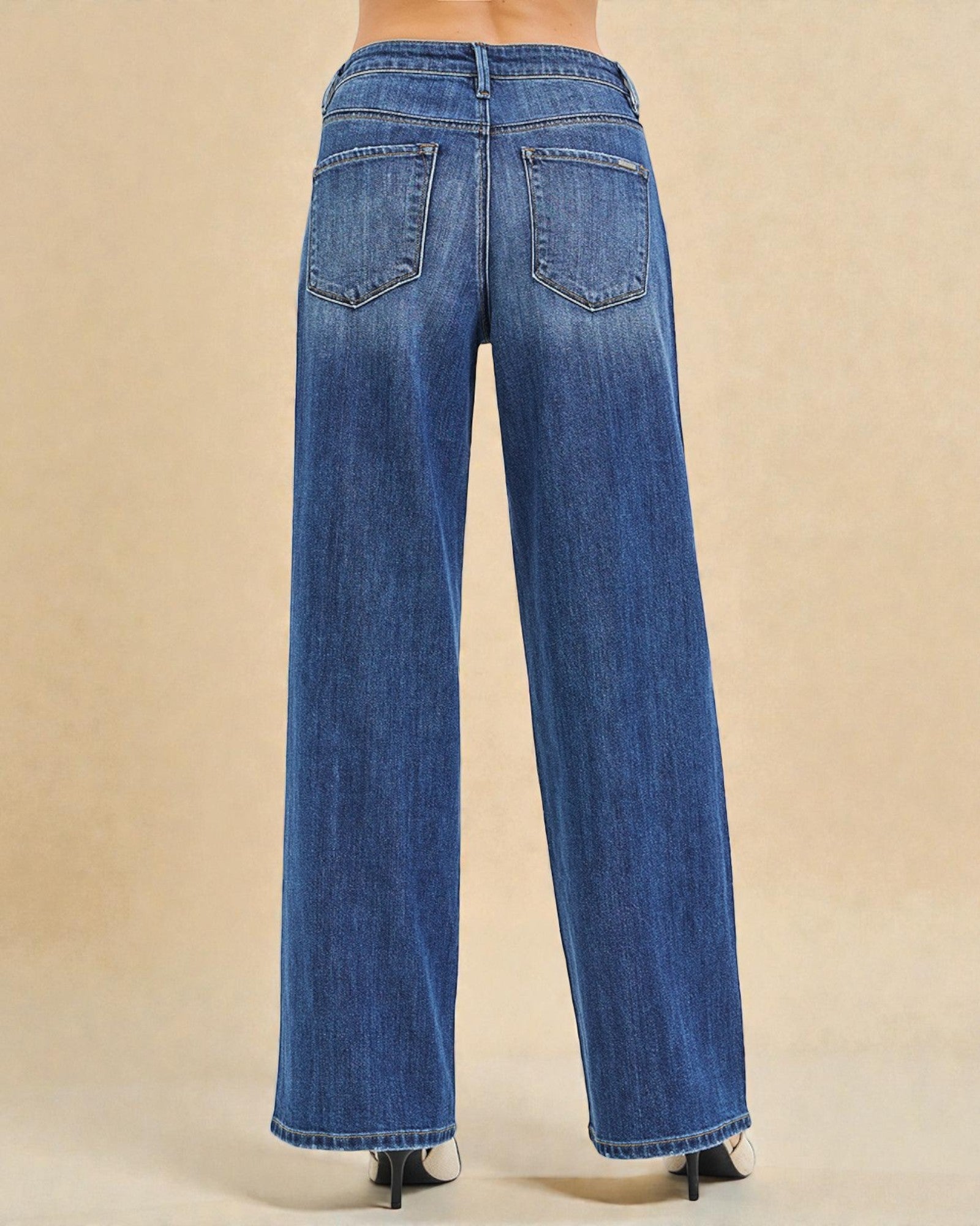 Blue jeans worn by a person on a beige background