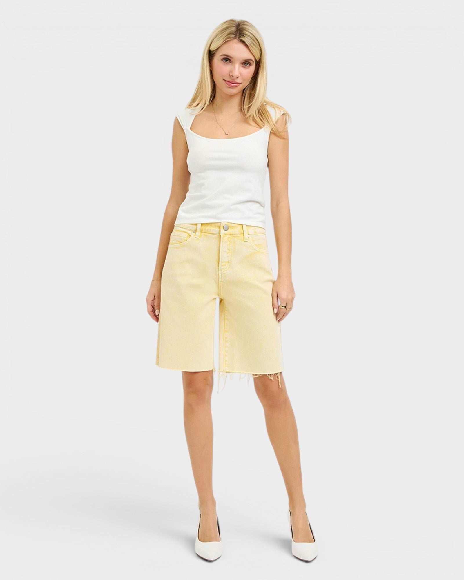 Woman wearing a white tank top and yellow shorts on a white background