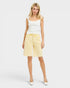 Woman wearing a white tank top and yellow shorts on a white background