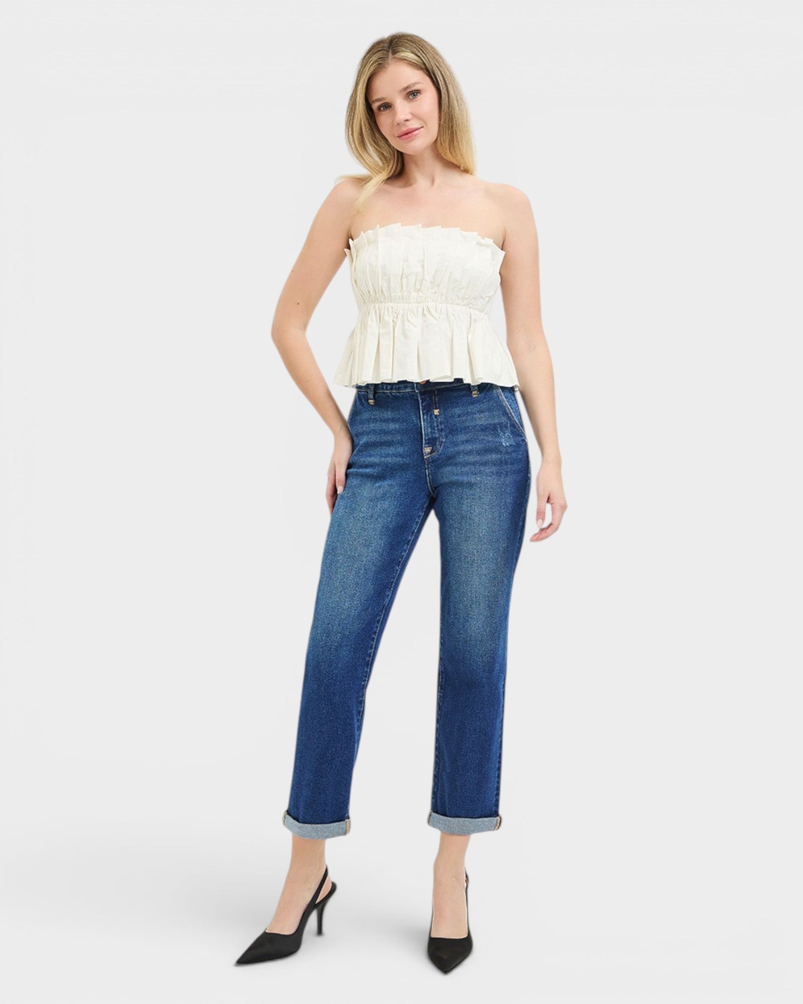 Woman wearing a white strapless top and blue jeans on a white background