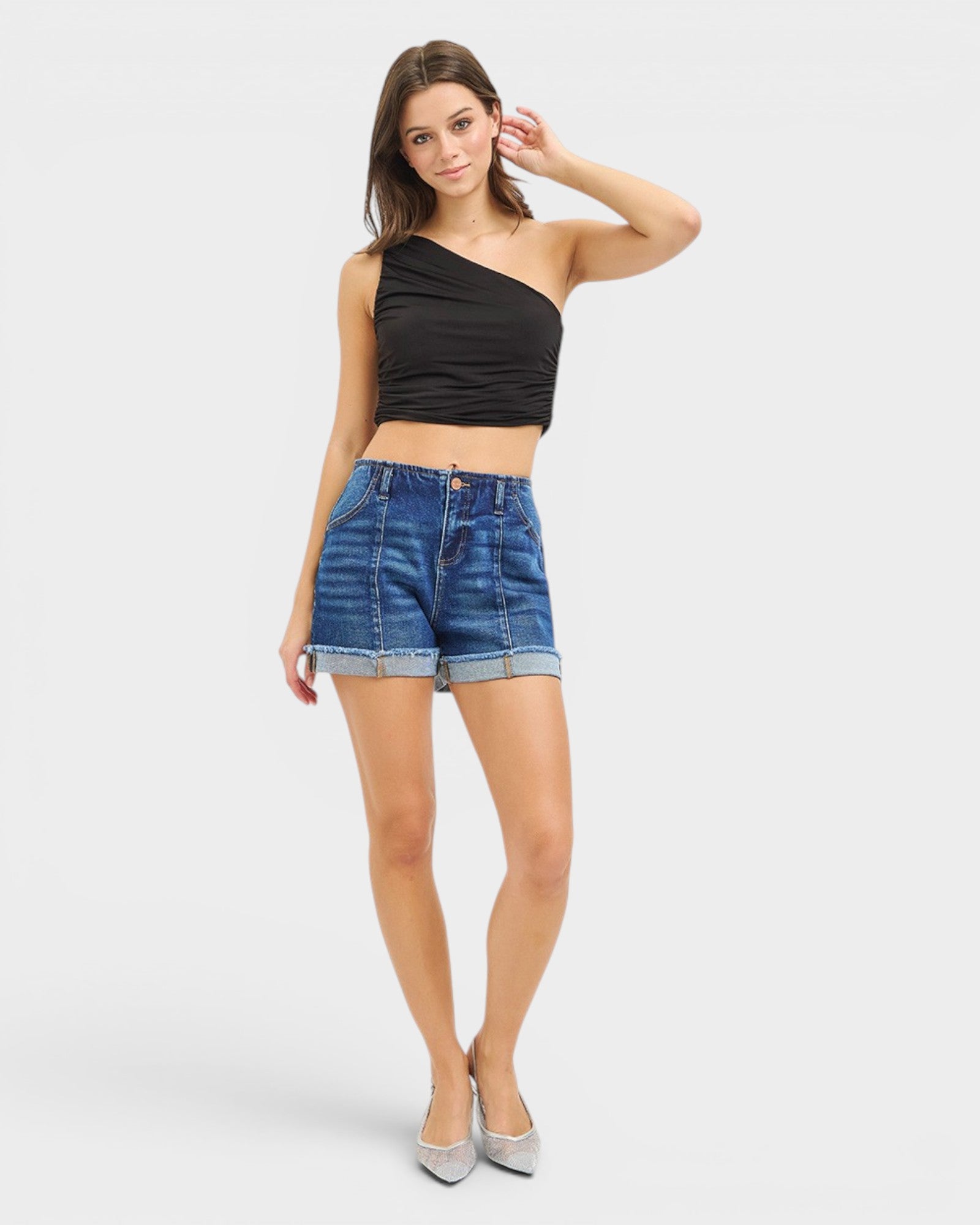 Woman wearing a black top and blue denim shorts on a white background
