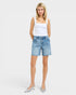 Woman wearing a white tank top and light blue denim shorts on a white background