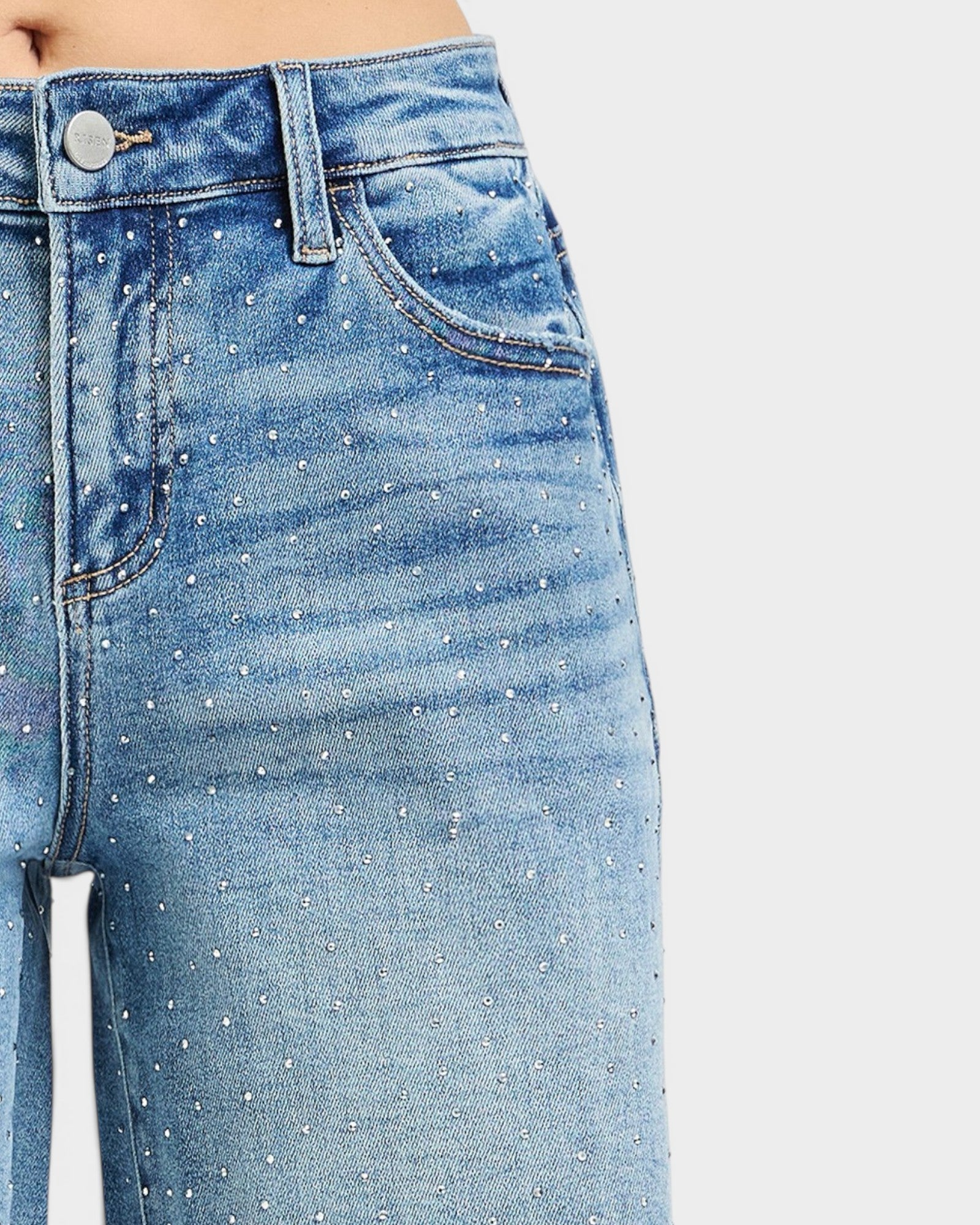 Close-up of blue jeans with rhinestone embellishments on a light gray background