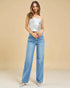 Woman wearing a white strapless top and blue jeans against a beige background