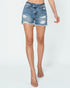 Denim shorts with a distressed look worn by a person on a white background
