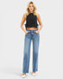 Woman wearing a black sleeveless top and blue jeans on a white background
