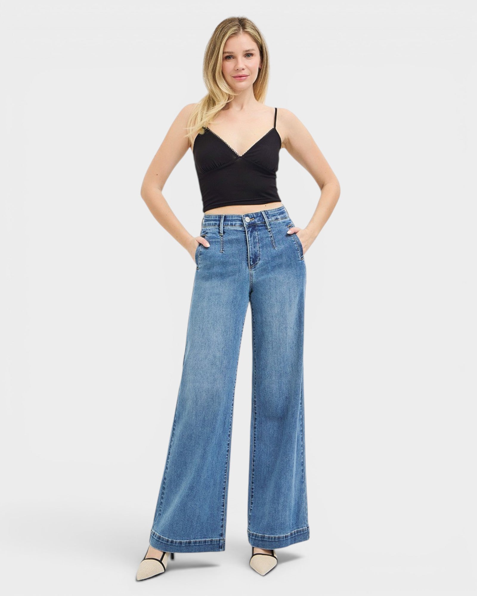 Woman wearing blue jeans and a black top on a white background