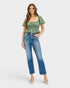 Woman wearing a green top and blue jeans on a white background