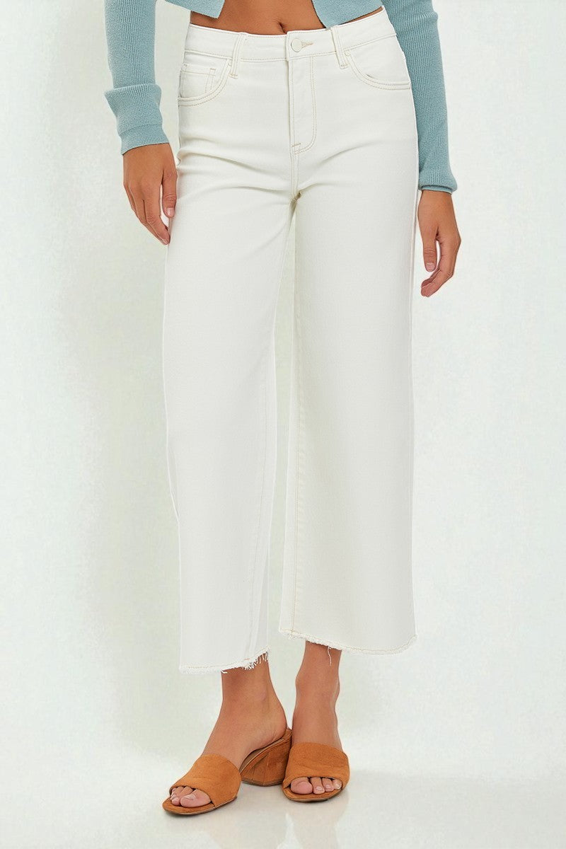 Person wearing white high-waisted jeans and brown sandals on a white background