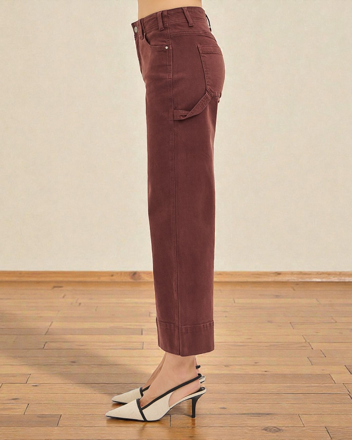 Brown pants worn by a person on a wooden floor with a beige wall background