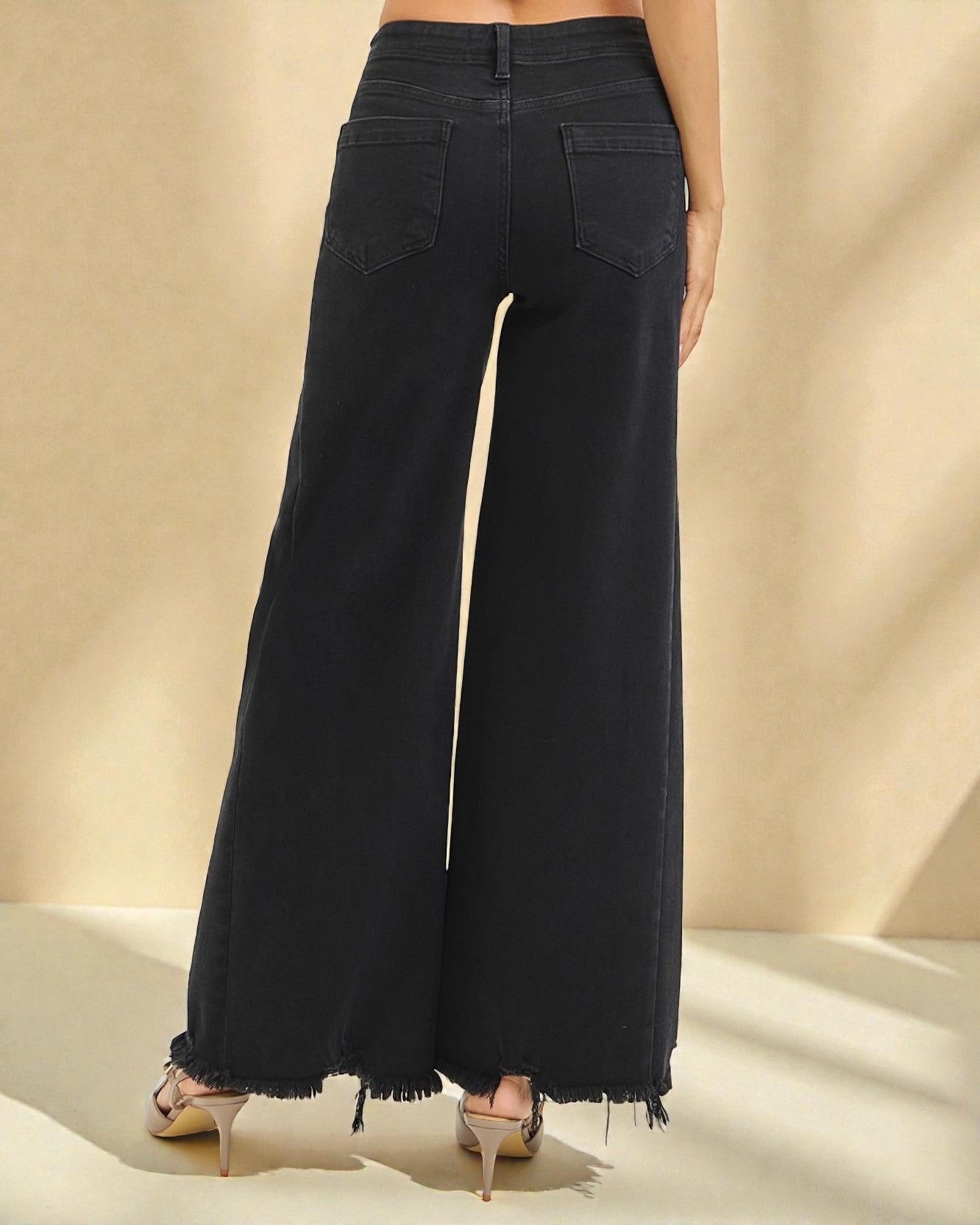 Black wide-leg jeans worn by a person on a beige background