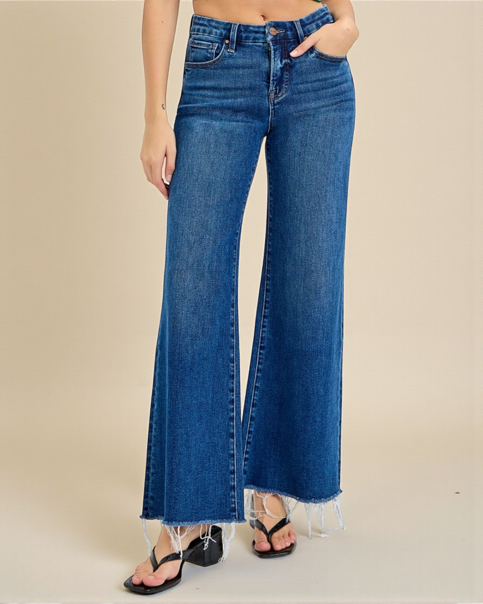 Blue jeans worn by a person on a beige background