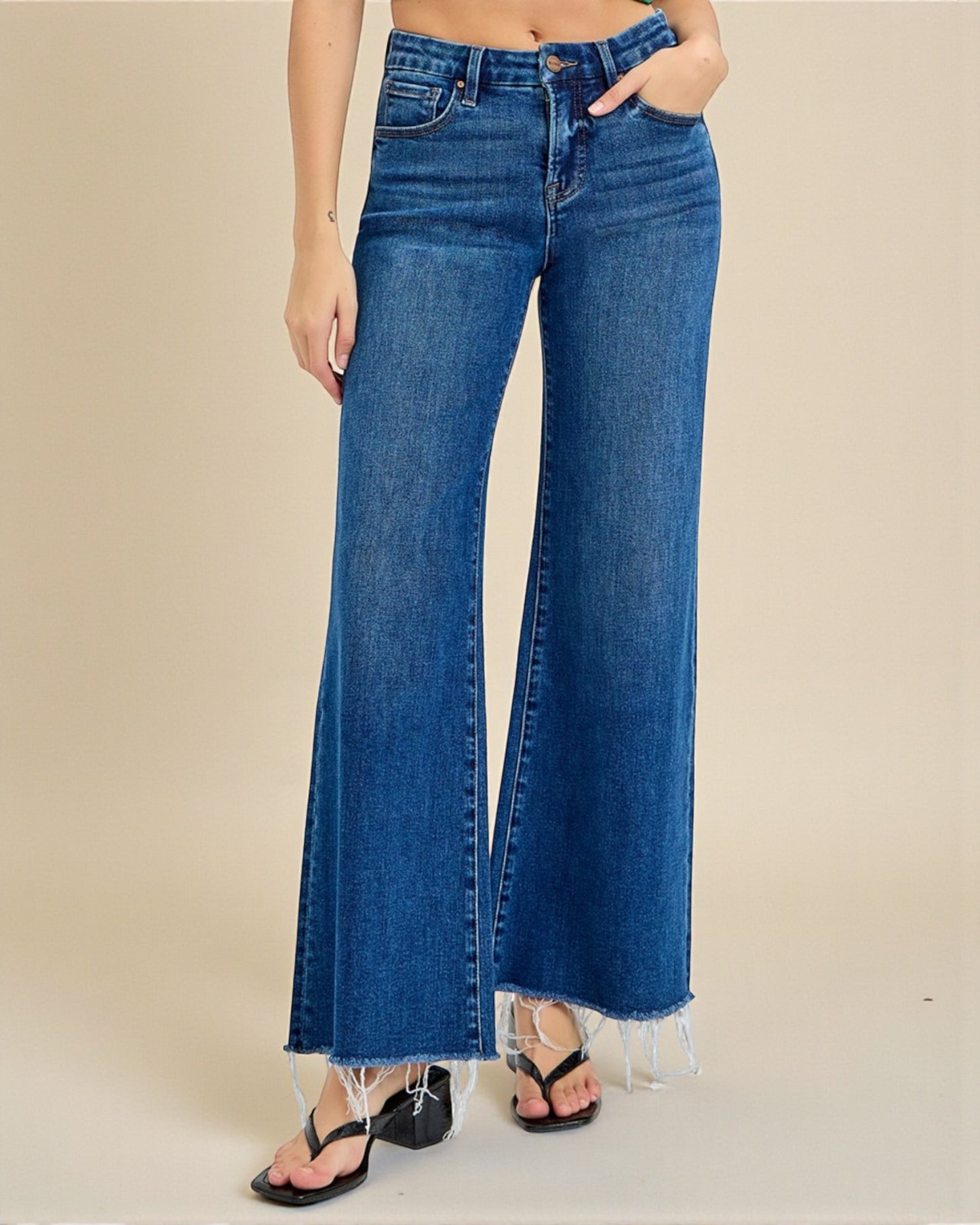 Blue jeans worn by a person on a beige background