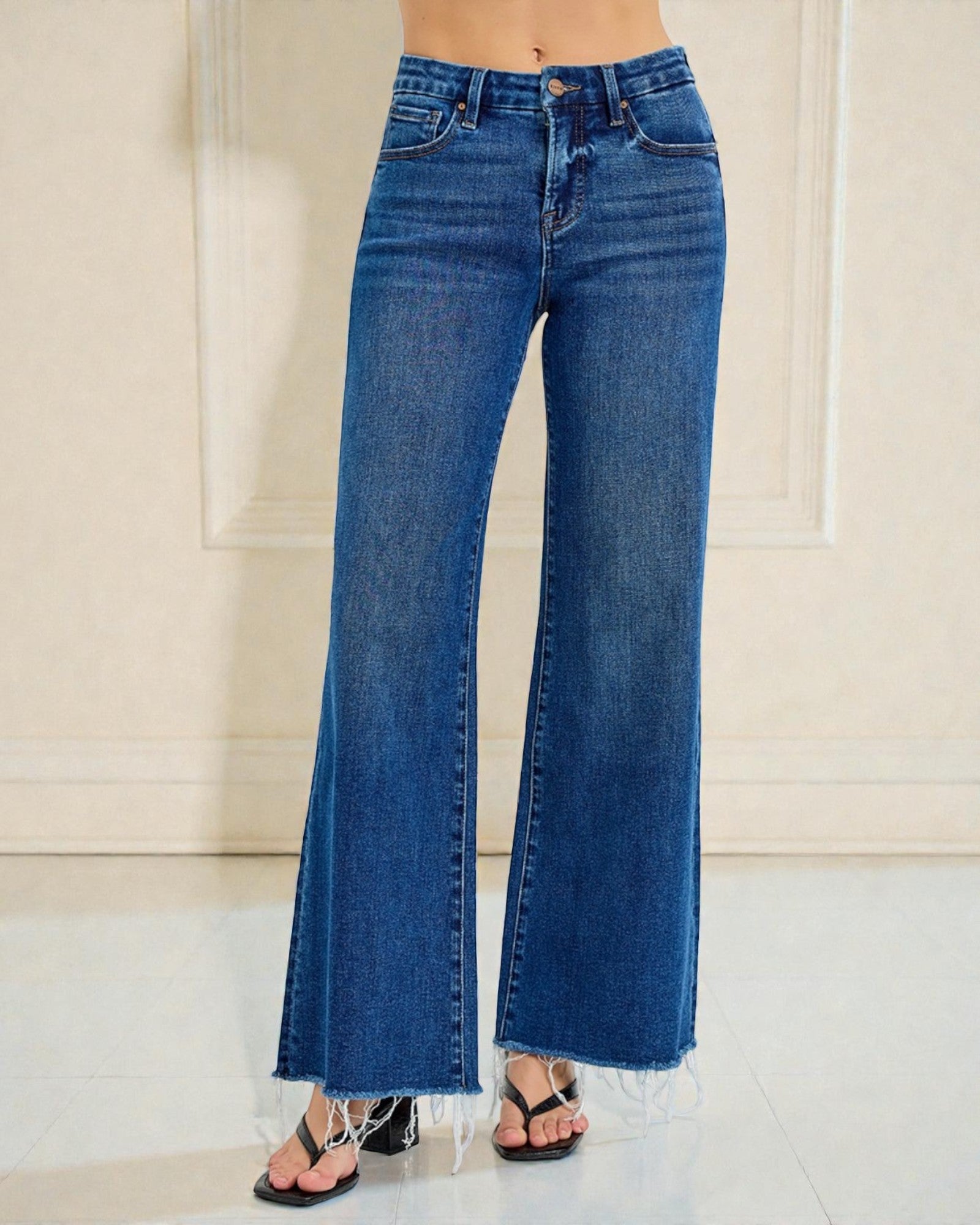 Blue flared jeans worn by a person on a neutral background