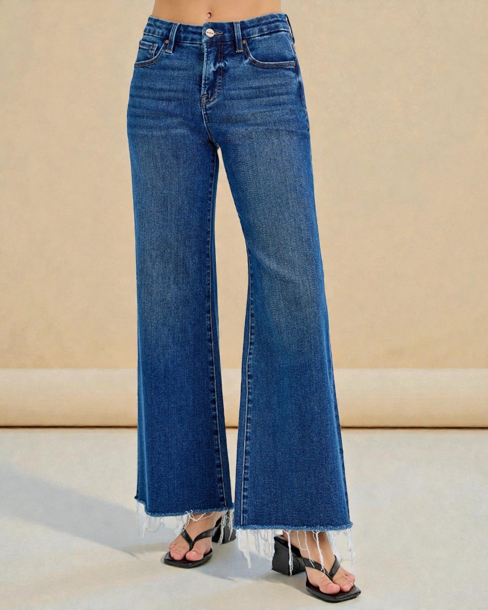 Blue jeans worn by a person on a beige background