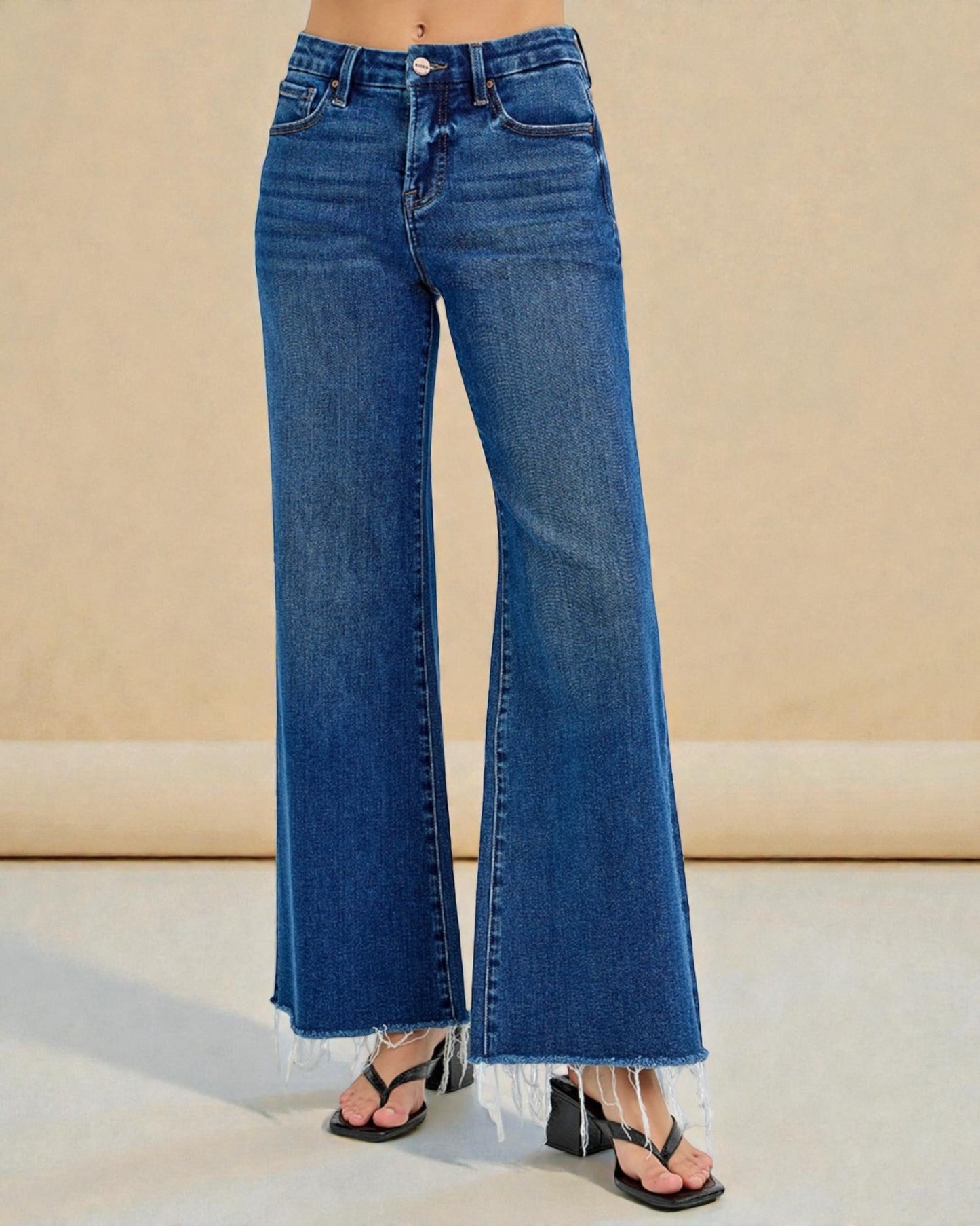 Blue jeans worn by a person on a beige background