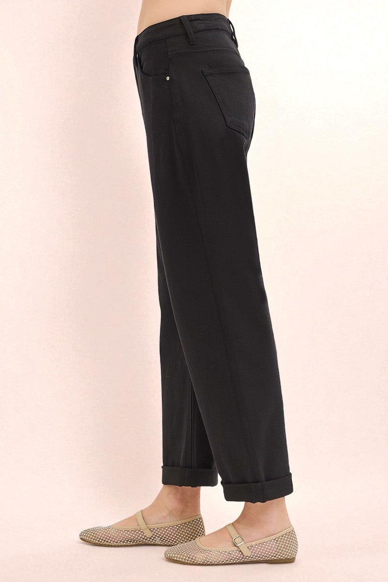 Black pants worn by a person on a light pink background