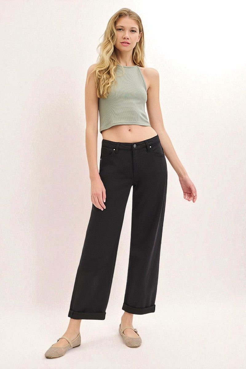 Woman wearing a green sleeveless top and black pants on a white background