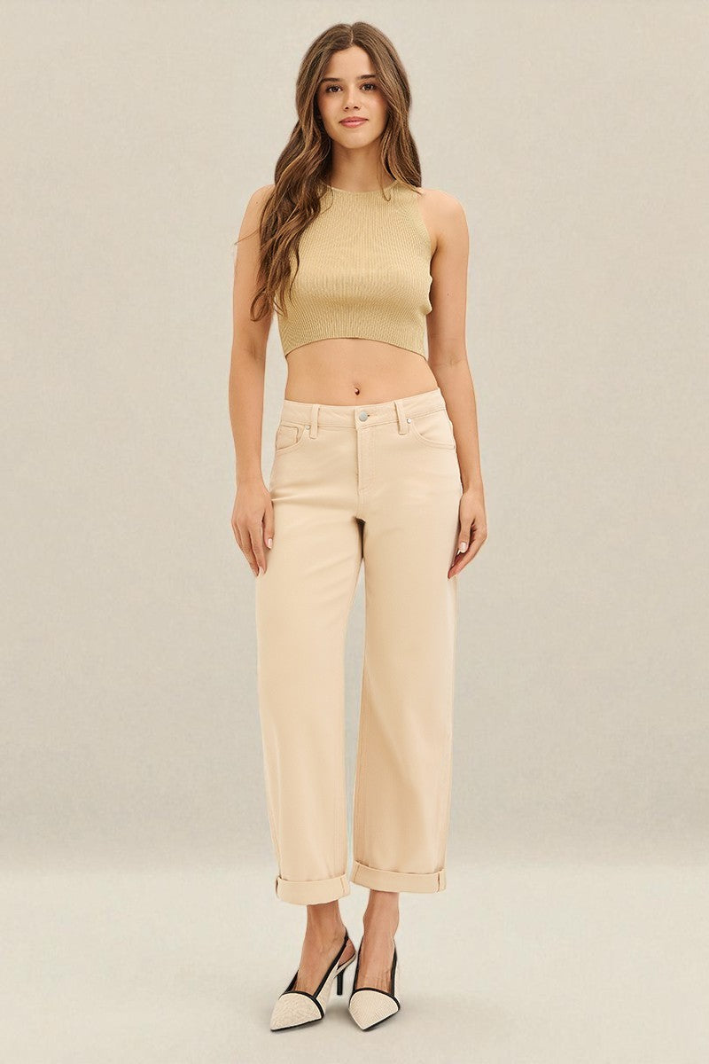 Woman wearing a beige sleeveless top and pants on a plain background