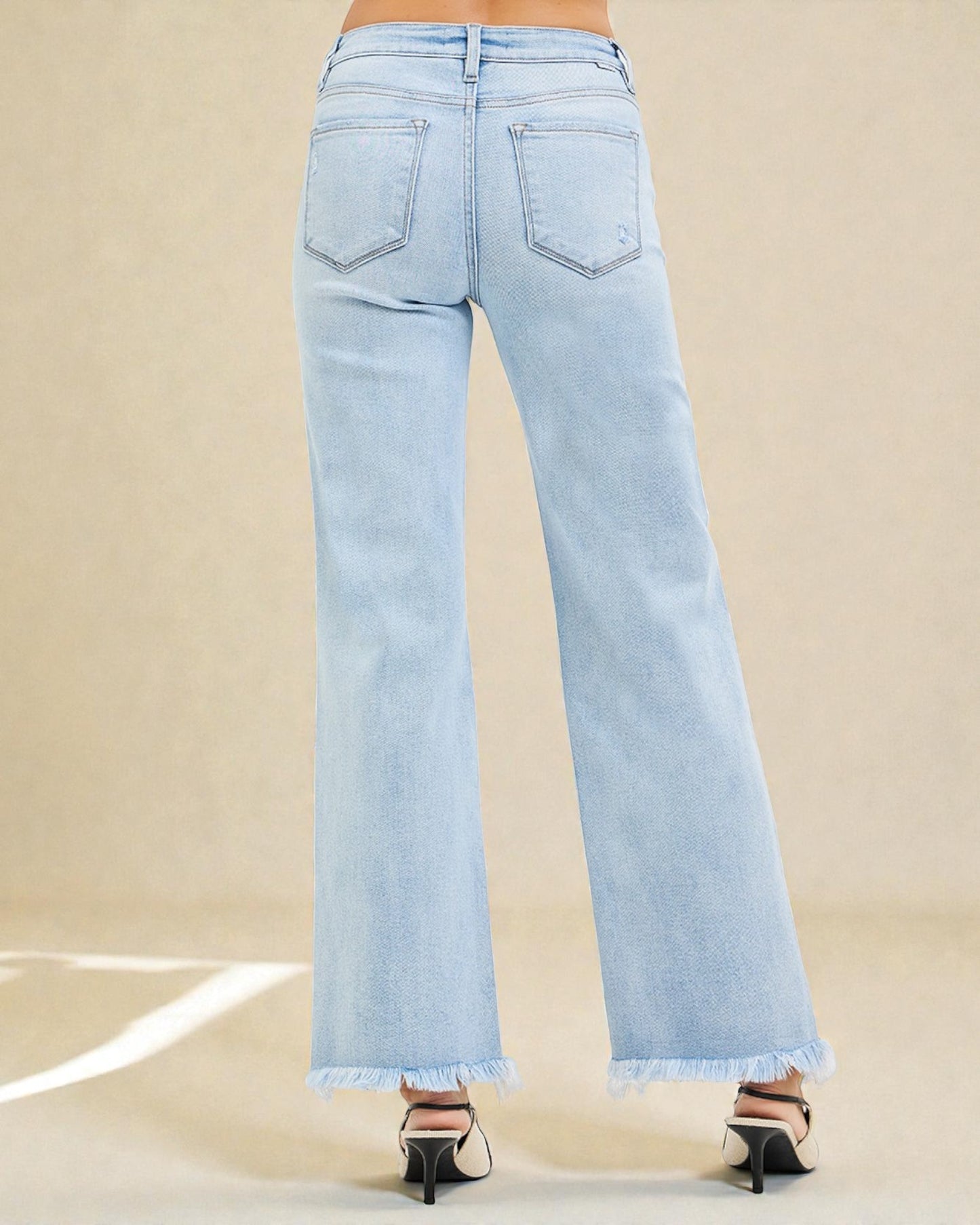 Light blue jeans with frayed hems on a beige background