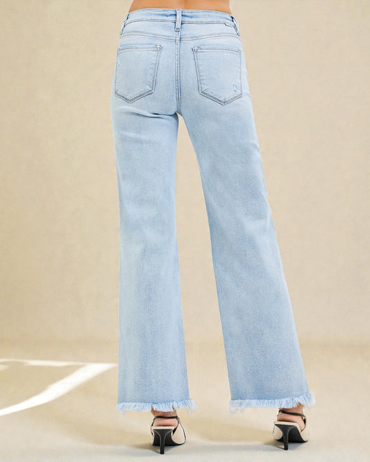 Light blue jeans with frayed hems on a beige background