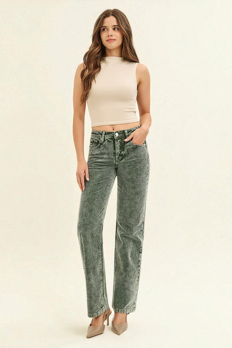 Woman wearing a beige sleeveless top and acid-wash jeans on a white background