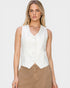 Woman wearing a white sleeveless blouse and brown pants on a plain background