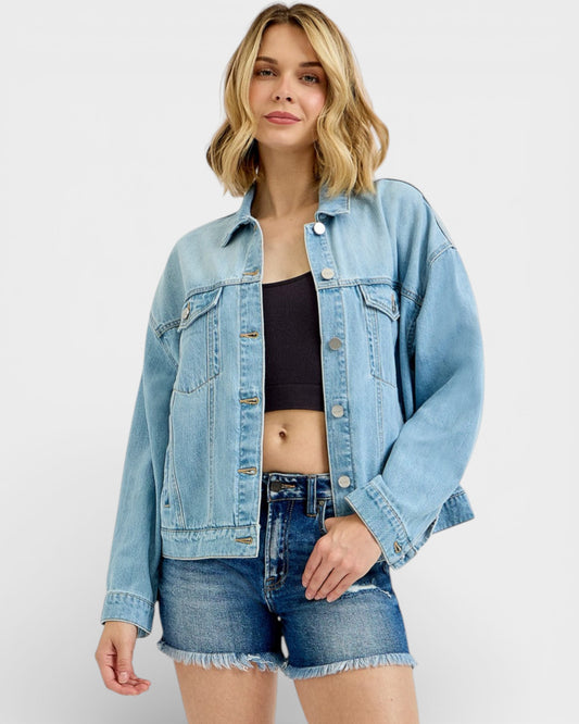 Woman wearing a light blue denim jacket and shorts on a white background